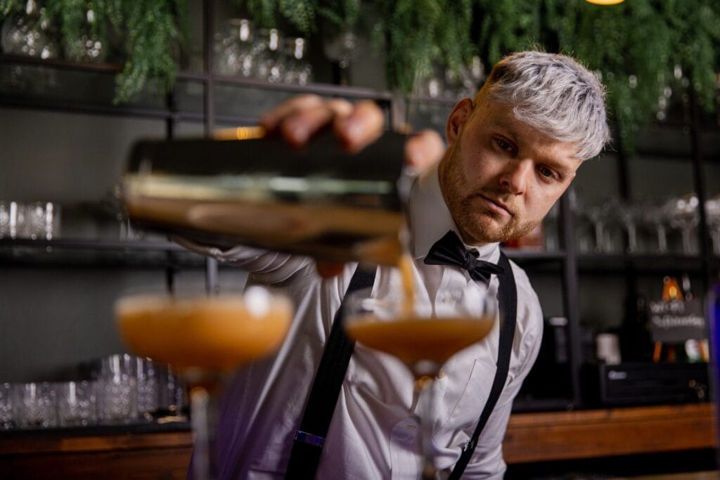 A butler in the buff shaking cocktails for a hen party