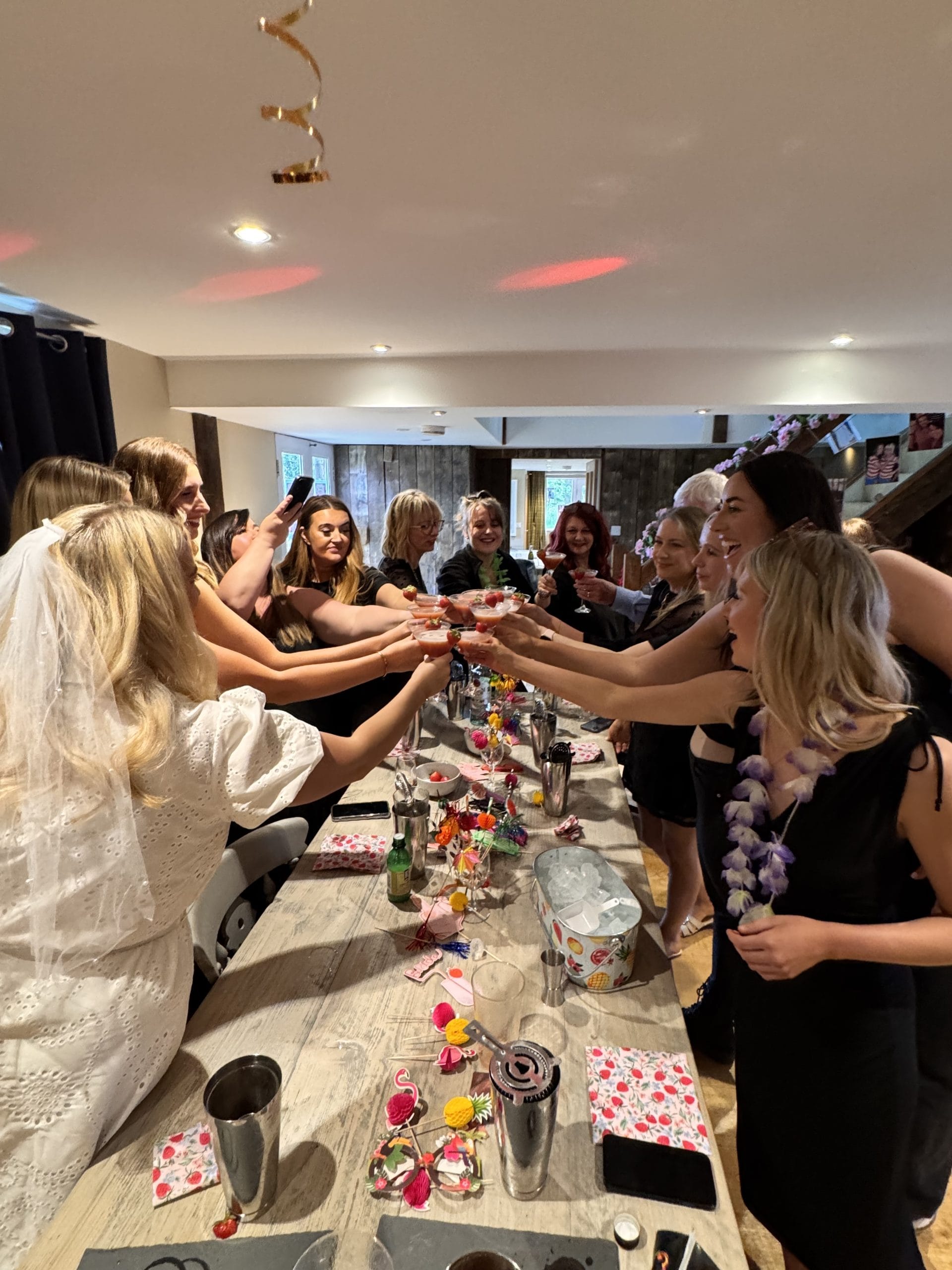 A hen party toasting the cocktails they made with their butler in the buff